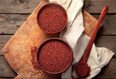 Red quinoa seeds on wooden background. Healthy vegan food concept. Top view