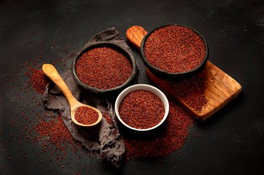 Red quinoa seeds on dark background. Healthy vegan food concept. 