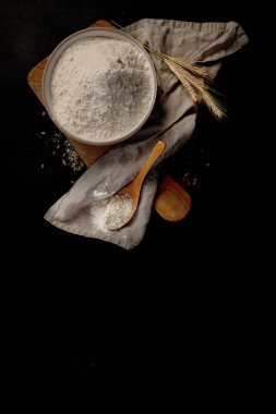 Wheat flour on dark background. Food preparing concept. Top view, copy space