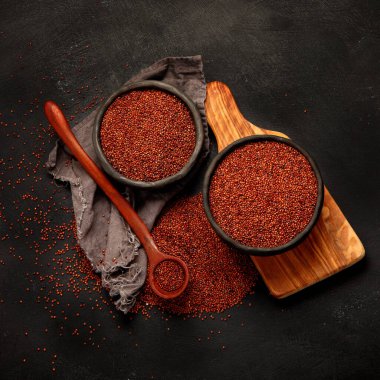 Red quinoa seeds on dark background. Healthy vegan food concept. Top view