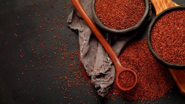 Red quinoa seeds on dark background. Healthy vegan food concept. Top view, copy space