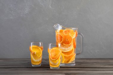 Gri ahşap masada portakallı limonata. Yaz içkileri konsepti. Ön görünüm