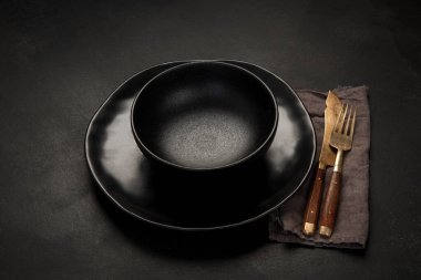 Table setting with a black plates on a black background. Minimalism concept. 