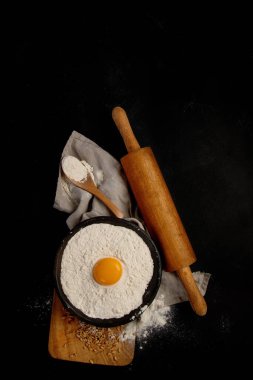 Wheat flour on dark background. Food preparing concept. Top view, copy space