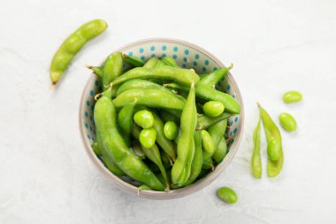 Çiğ edamame soya fasulyesi, açık gri arka planda tuz ve sos. Üst görünüm