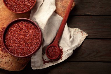 Red quinoa seeds on wooden background. Healthy vegan food concept. Top view, copy space