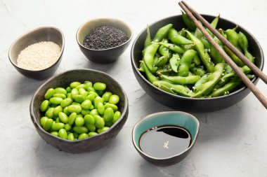 Çiğ edamame soya fasulyesi açık gri arka planda tuz ve sos ile. 