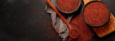 Red quinoa seeds on dark background. Healthy vegan food concept. Top view, copy space, panorama