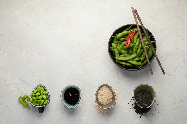 Çiğ edamame soya fasulyesi, açık gri arka planda tuz ve sos. Üst görünüm, alanı kopyala