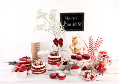 Lezzetli pasta ve kırmızı kapkekler beyaz arka planda. Kutlama için masayı hazırla. Tebeşir tahtası