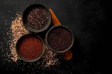 Koyu arkaplandaki farklı kinoa tipleriyle ayarlayın. Organik gıda konsepti. Üst görünüm, alanı kopyala