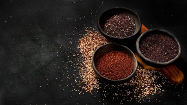 Koyu arkaplandaki farklı kinoa tipleriyle ayarlayın. Organik gıda konsepti. Boşluğu kopyala