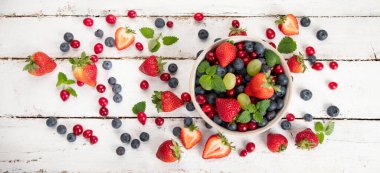 Beyaz arka planda çeşitli taze orman meyveleri. Organik gıda konsepti. Üst görünüm, kopyalama alanı, panorama