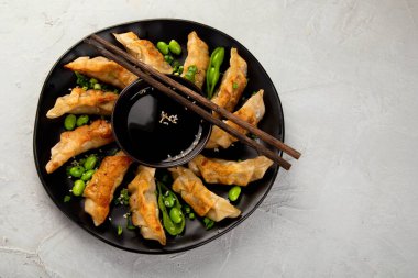 Soya soslu kızarmış gyoza köftesi ve açık gri arka planda soğan. Üst Görünüm, Boşluğu Kopyala