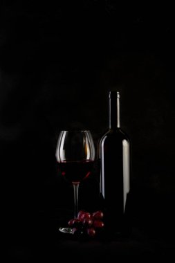 Kırmızı şarap şişesi, iki bardak ve siyah arka planda şişe açacağı. Boşluğu kopyala