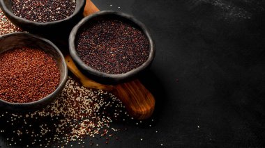 Koyu arkaplandaki farklı kinoa tipleriyle ayarlayın. Organik gıda konsepti. Boşluğu kopyala