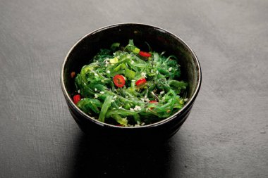 Gri arka planda susamlı ve biberli Wakame yosunu. Asya gıda kavramı. 