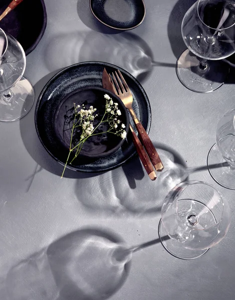 Gri arka planda siyah ve mavi plakalı masa ayarı. Minimalizm kavramı. Üst görünüm