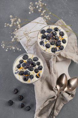 Taze yaban mersini ve gri arka planda krema ile yapılan ıvır zıvırlar. Porsiyon tatlılar. Üst görünüm