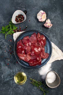 Çiğ çiğ ciğer, baharatlar ve gri arka planda pişirmek için hazırlanmış otlar. Üst görünüm, alanı kopyala