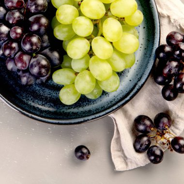 Gri arka planda siyah beyaz şarap üzümleri. Taze gıda konsepti. Üst görünüm, alanı kopyala