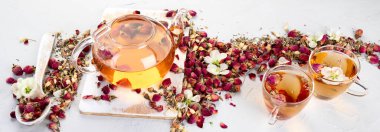 Fincanlı gül çayı ve açık gri arka planda çaydanlık. Panorama