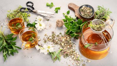 Fincanlı bitki çayı ve açık gri arka planda çaydanlık.. 