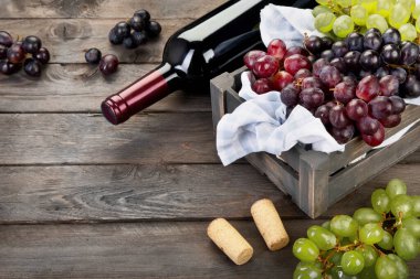 Ahşap arka planda siyah beyaz üzümlü bir şişe şarap. Boşluğu kopyala