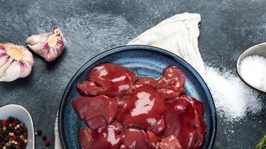 Çiğ çiğ ciğer, baharatlar ve gri arka planda pişirmek için hazırlanmış otlar. Üst görünüm, alanı kopyala