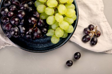 Gri arka planda siyah beyaz şarap üzümleri. Taze gıda konsepti. Üst görünüm