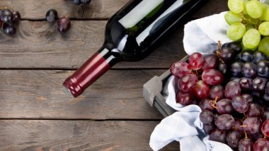 Ahşap arka planda siyah beyaz üzümlü bir şişe şarap. Üst görünüm, alanı kopyala