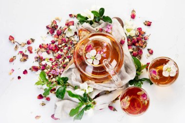 Fincanlı gül çayı ve açık gri arka planda çaydanlık. Üst görünüm