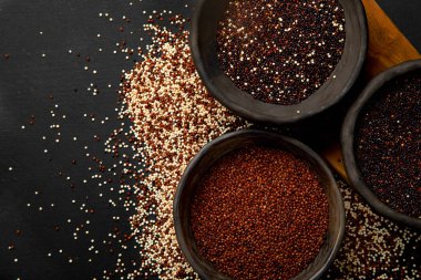 Koyu arkaplandaki farklı kinoa tipleriyle ayarlayın. Organik gıda konsepti. Üst görünüm, alanı kopyala