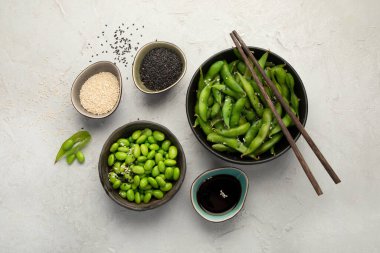 Çiğ edamame soya fasulyesi, açık gri arka planda tuz ve sos. Üst görünüm