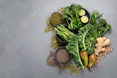 Gri arka planda çeşitli yeşil sebzeler ve mısır gevreği. Sağlıklı gıda konsepti. Üst görünüm, alanı kopyala