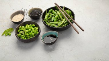 Çiğ edamame soya fasulyesi açık gri arka planda tuz ve sos ile. 