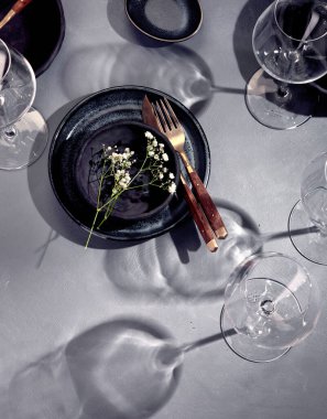 Gri arka planda siyah ve mavi plakalı masa ayarı. Minimalizm kavramı. Üst görünüm