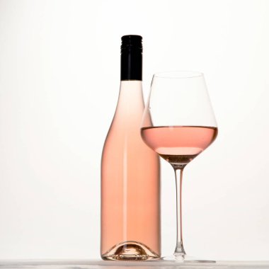 Beyaz arka planda bir bardak gül şarabı tutan genç bir kadın. Siyah ojeli el..