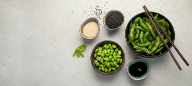 Çiğ edamame soya fasulyesi, açık gri arka planda tuz ve sos. Üst görünüm, alanı kopyala