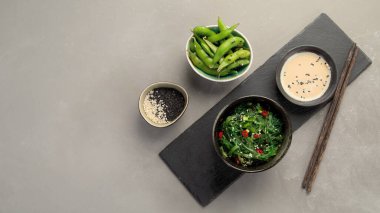 Gri arka planda susamlı ve biberli Wakame yosunu. Asya yemekleri konsepti. Üst görünüm, alanı kopyala