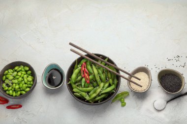 Çiğ edamame soya fasulyesi, açık gri arka planda tuz ve sos. Üst görünüm, alanı kopyala