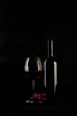 Kırmızı şarap şişesi, iki bardak ve siyah arka planda şişe açacağı. Boşluğu kopyala