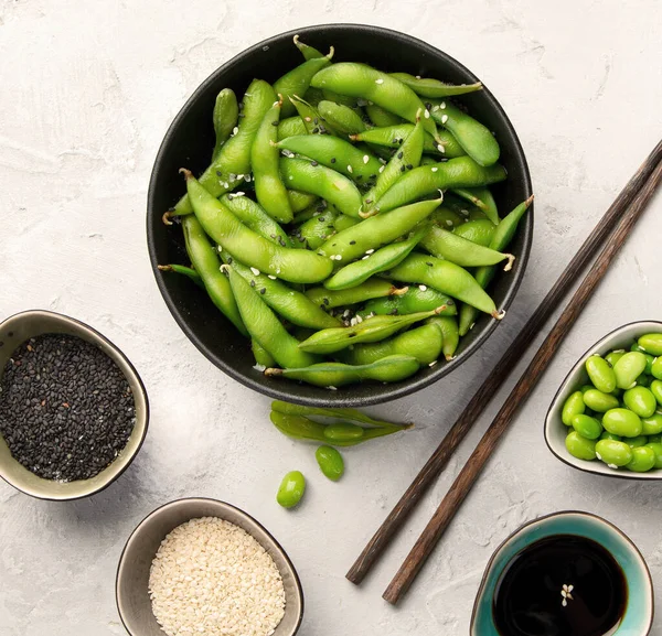 Çiğ edamame soya fasulyesi, açık gri arka planda tuz ve sos. Üst görünüm