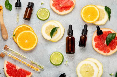 Açık gri arka planda narenciye aromalı bir şişe önemli aroma yağı. Üst manzara, düz uzanma