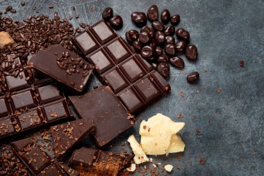 Gri arka planda kakao fasulyesi ve çikolata. Üst görünüm, düz görünüm, kopyalama alanı