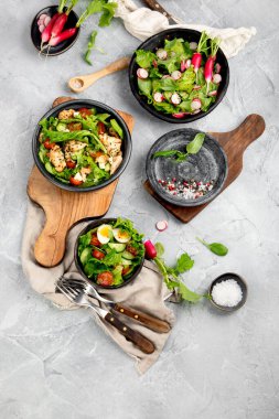 Açık gri arka planda taze yapılmış salatalar. Mevsimlik gıda konsepti. Üst görünüm, alanı kopyala