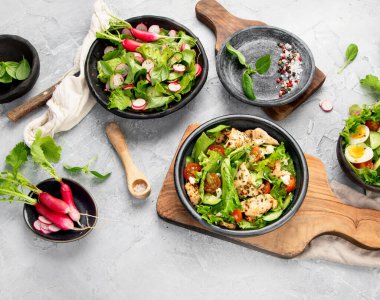 Açık gri arka planda taze yapılmış salatalar. Mevsimlik gıda konsepti. Üst manzara, düz uzanma