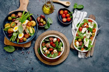 Koyu gri arka planda çeşitli salatalar. Mevsimlik gıda konsepti. Üst görünüm, düz görünüm, kopyalama alanı