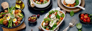 Koyu gri arka planda çeşitli salatalar. Mevsimlik gıda konsepti. Panorama