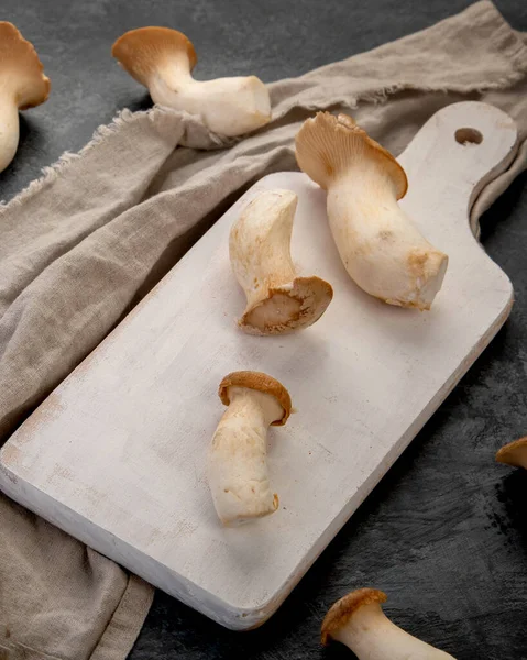 黑暗背景下的牡蛎王蘑菇 Eringi在切板上 复制空间 — 图库照片